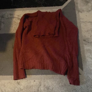 Röd stickad polotröja - Säljer en mysig röd stickad polotröja med ribbade detaljer. Perfekt för kyliga dagar med sin höga krage och långa ärmar. Tröjan har en härlig textur och är både stilren och bekväm.