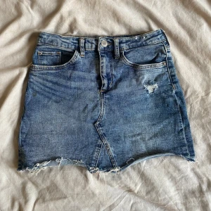 Mörkblå jeanstjol  - Mörkblå jeanstjol med slitningar i fram, Storlek 134! Bra skick!!💕🙌