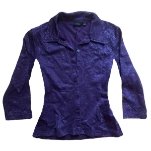 Lila glittrig skjorta från Lindex - Säljer en snygg lila skjorta från gammalLindex med glittrigt material och trekvartsärmar. Fick från min moster, men används inte.  💜