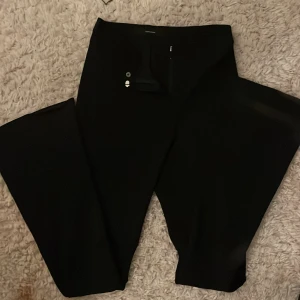 Svarta kostym byxor från Vero Moda - Snygga svarta kostym byxor från Vero Moda med hög midja och dragkedja. De har en stilren design och passar perfekt för en chic look. Byxorna har en rak passform och är tillverkade i ett bekvämt material.