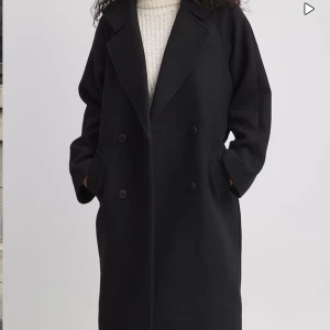 Svart lång kappa i ullblandning - Snygg svart kappa i ullblandning från nakd, använd en gång men kommer inte till användning då jag har en annan kappa💓 helt slutsåld köpt för 1399