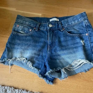 Blå jeansshorts från Gina Tricot  - Säljer ett par snygga blå jeansshorts från Perfect Jeans, Gina tricot. De har en klassisk femficksdesign och fransiga kanter för en avslappnad look. Perfekta för sommardagar!