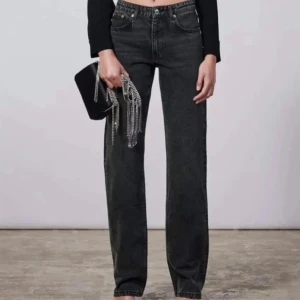 Svarta jeansbyxor - Snygga svarta jeansbyxor med en klassisk straight passform. De har en låg midja och är perfekta för en stilren look. Byxorna har knappar och dragkedja framtill.