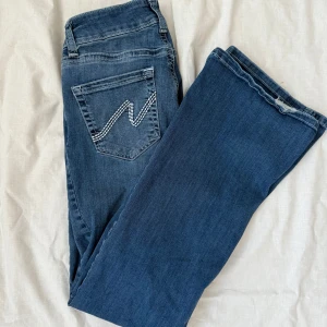 Blå bootcut jeans från Nelly  - Jättefina blå bootcut jeans från Nelly med broderad detalj på bakfickan (storlek EU38). Jeansen har normal passform och är  i mjukt denimtyg så är även lite stretchiga i materialet. Säljer då de blivit lite för stora. Enda defekten är att de är lite slitna längst ned bak på byxbenen (se bild) annars bra skick! Längden är den normala, inte short. Nypris 699kr