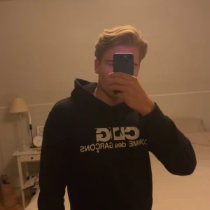 Svart CDG hoodie från Comme des Garçons - Svart hoodie från Comme des Garçons med stor vit CDG-logga på bröstet.Skicket är extremt bra. Skön passform men är mer mot S hållet. Materialet är 100% bomull. Jag har äktesverifiering så de är bara att skriva. Köpt i Japan i Commes des Garçons egna butik i Tokyo🙌Priset är inte hugget i sten🙏