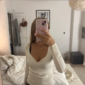 Vit ribbad långärmad - Säljer en vit ribbad långärmad topp från H&M i storlek XS. Toppen har en djup v-ringning och är figurnära med stretchigt material. Knappt använd 