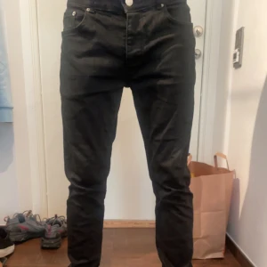 Svarta tapered jeansbyxor - Säljer ett par svarta jeansbyxor med tapered passform och klassisk femficksdesign. Byxorna har normal midja och är tillverkade i jeansmaterial. Perfekta för dig som gillar en stilren look med lite smalare ben. Passar till sneakers och hoodie.