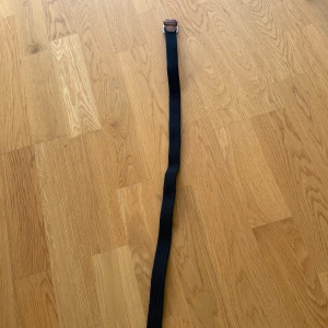 Svart flätat bälte från Jack & Jones 80cm  - Snyggt svart flätat bälte från Jack & Jones med detaljer i brunt skinn och en robust silverspänne. Perfekt accessoar för att lyfta din outfit med en stilren och klassisk look. Bältet har en vävd struktur och läderdetaljer vid spännet. 80cm. Köpt för 250kr mitt pris 130kr.