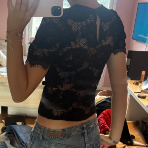 Svart spetsblus från Gina Tricot - Supersnygg svart blus från Gina Tricot i storlek S. Blusen är helt i spets med blommigt mönster, korta ärmar och rund hals. 