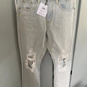 Ljusa ripped jeans från Somedays Lovin - Säljer ett par ljusblå jeans från Somedays Lovin i modellen Iceblu. Jeansen har snygga slitningar och stora hål vid knäna för en edgy look. Klassisk femficksmodell med raka ben och gul kontrastsöm. Perfekta för dig som gillar streetstyle.