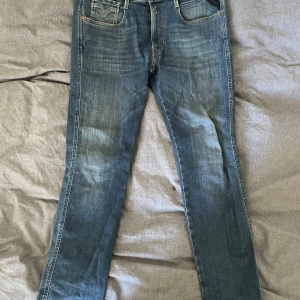 Blå Replay jeans slim fit - Snygga blå jeans från Replay med skinny passform och klassisk femficksdesign. Jeansen har ljusa slitningar och tydliga sömmar på bakfickorna. Tillverkade i stretchigt denim för en bekväm känsla och stilren look. Tveka inte att skriva om du vill ha fler bilder!