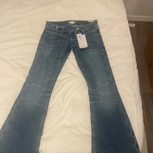 Blå bootcut jeans från Gina Tricot - Jag säljer dessa snygga blåa jeansen från Gina 14+ i storlek S. De har aldrig använts och lappen är fortfarande på! De är lågmidjade och har tre hål💞