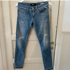 Blå Replay jeans med slitningar - Snygga blå jeans från Replay med klassisk femficksdesign och diskreta slitningar framtill. Jeansen har smal passform och normal midja, perfekt för en avslappnad men trendig look. Materialet är mjukt denim som sitter skönt hela dagen.