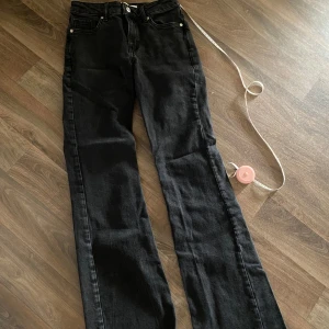 Gråsvarta bootcut jeans  - Snygga gråsvarta jeans med bootcut passform och rå, fransig kant nertill. Klassisk femficksmodell med dragkedja och knapp. Jeansen har en hög/mellan midja. Perfekta för dig som gillar en avslappnad men trendig look.
