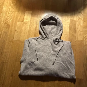 Grå hoodie med snörning - Snygg beige kaschmir hoodie med huva och snörning. Mjuk och skön känsla, aldrig använd. Klassisk modell utan tryck eller mönster, passar dig som gillar enkel stil. Dragsko i huvan med metalländar för extra detalj.