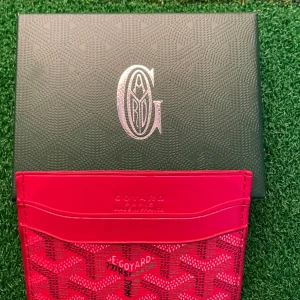 Röd plånbok med mönster - Säljer en snygg röd plånbok  med deras ikoniska grafiska mönster. Plånboken har flera kortfack och är tillverkad i skinn med tryckt logga och detaljer. Perfekt för dig som vill ha något unikt och stilrent i fickan.