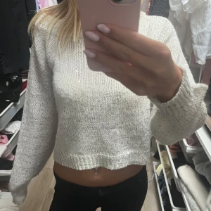 Glittrig vit stickad tröja - Superfin vit stickad tröja med glittriga paljettdetaljer. Modellen är croppad med lång ärm och ribbade muddar. Perfekt för dig som vill ha en mysig men ändå lite extra tröja till höst och vinter. Snygg att styla med både jeans och kjol.