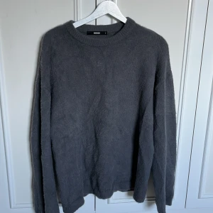 Mörkgrå stickad tröja från BikBok i ullmix - Mysig mörkgrå stickad tröja från BikBok i storlek S. Tröjan har en enkel design med rund halsringning och långa ärmar. Perfekt för lager-på-lager och chill dagar. Materialet är fluffigt och ullmix så otroligt varm och skön till höst och vinter!
