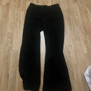 Kostymbyxor - Svarta kostymbyxor som är högmidjade, med ett resår som går hela vägen ner på benet.