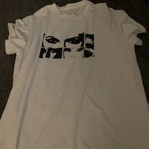 Vit t-shirt med grafiskt tryck från SHEIN - Vit t-shirt från SHEIN med svart grafiskt tryck av ögon och ansikten på bröstet. Klassisk passform och rund halsringning. Perfekt för en cool och avslappnad stil.