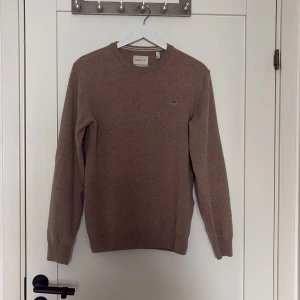 Beige stickad tröja från GANT - Säljer en klassisk beige stickad tröja från GANT i superfin lammull. Tröjan har rund halsringning, långa ärmar och diskret logga på bröstet. Perfekt för lager-på-lager och passar till det mesta. Skick 10/10 endast använd några gånger. Köpt för runt 1000kr säljer för endast 149kr💯