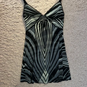 Zebramönstrad kortklänning med spetsdetaljer - Säljer en snygg kortklänning med zebramönster i svart och grått. Klänningen har smala axelband, spetsdetaljer upptill och en lätt utsvängd passform. Perfekt för dig som gillar djurmönster och vill sticka ut.