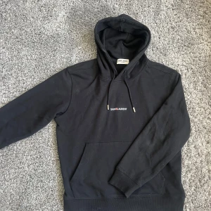 Svart hoodie från Saint Laurent - Säljer en svart hoodie från Saint Laurent med vit logga på bröstet. Tröjan är i ny skick och tagg följer med!! Byten är intressant!!!🍾🍾🍾