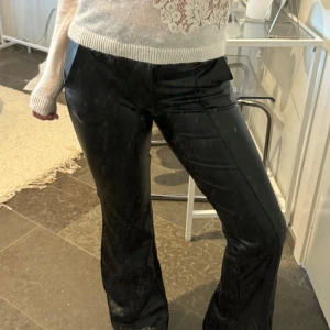 Svarta skinnbyxor - Snygga svarta skinnbyxor med bootcut-modell. Byxorna har normal passform och säljer dessa pga att jag inte använder dom. De är alltså i nytt skick då de har andvänts vid ett enda tillfälle. ( spegeln är smutsig, ej byxorna!)