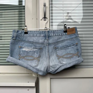 Ljusa jeansshorts från Abercrombie & Fitch - Snygga ljusa jeansshorts från Abercrombie & Fitch med slitna detaljer och uppvikta ben, använda men fortfaranre i bra skick. Skulle säga att de passar en S/M💓Har ingen bild på!!💓De är 40cm rakt över midjan💕