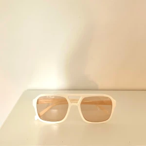 Snygga solglasögon med beige glas - Snygga solglasögon med vit, fyrkantig båge och beige tonade glas. Modellen har en modern och lite oversized känsla, perfekt för att sticka ut i sommar☀️ Passar dig som gillar stilrena accessoarer med en twist🤵🏼