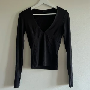 Svart topp Gina Tricot  - Säljer en svart topp från Gina Tricots soft touch kollektion 💞 den är urringad och har ”tumvantar” obs! Den har fått ett litet hål vid ena ”tumvanten” 😙