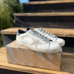 Golden Goose - Säljer ett par vita sneakers från Golden Goose med grå stjärndetalj på sidan och mörkblå häl. Använda lite som man kanske ser på sulan. Skick 9/10. Billigare vid smidig affär👍