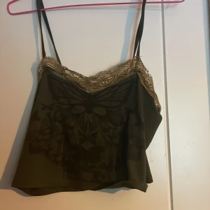 Olivgrön croppad linnetopp med spets från Romwe - Säljer en olivgrön croppad linnetopp från Romwe med tunna axelband. Spetsen på ena sidan har släppt men går att laga för hand.