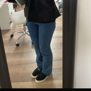 Blå bootcut jeans från Gina tricot  - Säljer ett par klassiska blå bootcut jeans från Gina Tricot. Jeansen har normal passform, dragkedja och knapp framtill samt tydliga sömmar. Perfekta för dig som gillar en tidlös stil med lite utsvängda ben.