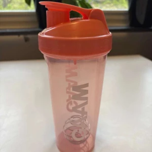 Rosa shaker från Smart gym - Säljer en rosa shaker från Smart gym med vitt tryck på sidan. Shakern har ett skruvlock, praktiskt snäpplock och en metallvisp inuti för att blanda drycker. Perfekt för proteinshakes eller andra träningsdrycker.