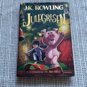 Julegrisen - Julegrisen är en barnbok av J.K. Rowling, illustrerad av Jim Field. Omslaget visar en pojke och en rosa gris under en julgran, med färgglada juldekorationer och paket. Boken har ett juligt tema och är på svenska.