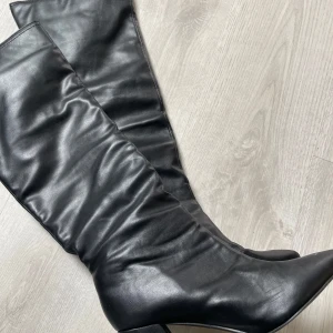 Svarta höga stövlar med klack - De perfekta bootsen! Slutar strax under knäna, har en lite lösare/slappare passform runt vaderna och en superbekväm klack! Passar till allt i alla årstider🌞