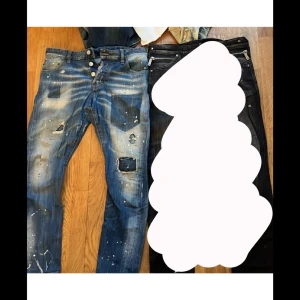 Blå slitna jeans från Dsquared2 - Säljer ett par blå jeans från Dsquared2 med slitningar, hål och färgstänk. Jeansen har knappar i gylfen och klassisk femficksmodell. Snygg vintage-look och coola detaljer, perfekt för dig som gillar streetstyle.