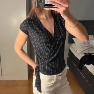 Svart omlottopp - Säljer en svart omlottopp med färgglada ränder. Såå cool och fin