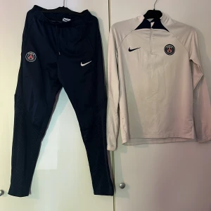 Vit träningströja från Nike PSG och byxor - Säljer en vit långärmad träningströja från Nike psg och byxorna som tillhör tröjan. Storlek på tröjan är 156-179 och på byxorna är storleken 158. 