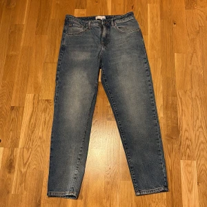 Blå jeans med lose fit  - Säljer ett par klassiska blå jeans med lose fit passform och raka ben. Jeansen har fem fickor, dragkedja och knapp framtill samt diskreta slitningar för en snygg look. Perfekta till vardags och passar till det mesta. Dem har en liten fläck på vänster ficka men inget som stör looken.