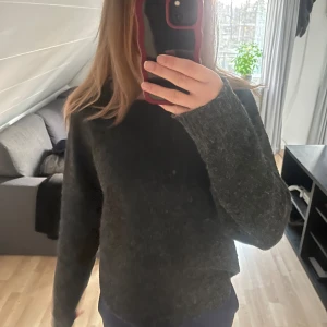 Mörkgrå stickad tröja - Mysig mörkgrå stickad tröja med lång ärm och klassisk passform. Perfekt för kyligare dagar och enkel att matcha med olika outfits. Snygg och enkel design utan synliga detaljer.