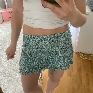 Grön blommig volangkjol - Supersöt volang kjol blomstermönster och snören! Den har dessutom inbyggda shorts i samma tyg! 