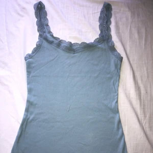 Blå ribbad linne - Säljer en snygg blå ribbad linne från Esmara med spetsdetaljer vid halsringning och axelband. 