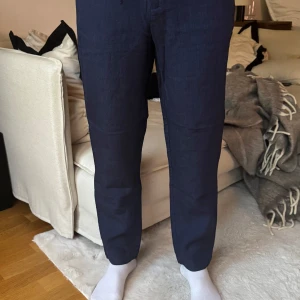 Mörkblå linnebyxor - Snygga mörkblå linnebyxor med en avslappnad passform. Byxorna har en rak stil och är perfekta för en stilren look. De har praktiska fickor framtill och en bekväm midja.