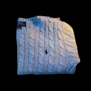  Polo Ralph Lauren ÄKTA - Säljer en ÄKTA stilren Polo Ralph Lauren kofta i färg av grå, den är stickad och är i fint skick. Tröjan har en klassisk rund halsringning och det ikoniska logotypbroderiet på bröstet. Perfekt för kyligare sommardagar dagar med sin mjuka och bekväma passform. Står för frakt!
