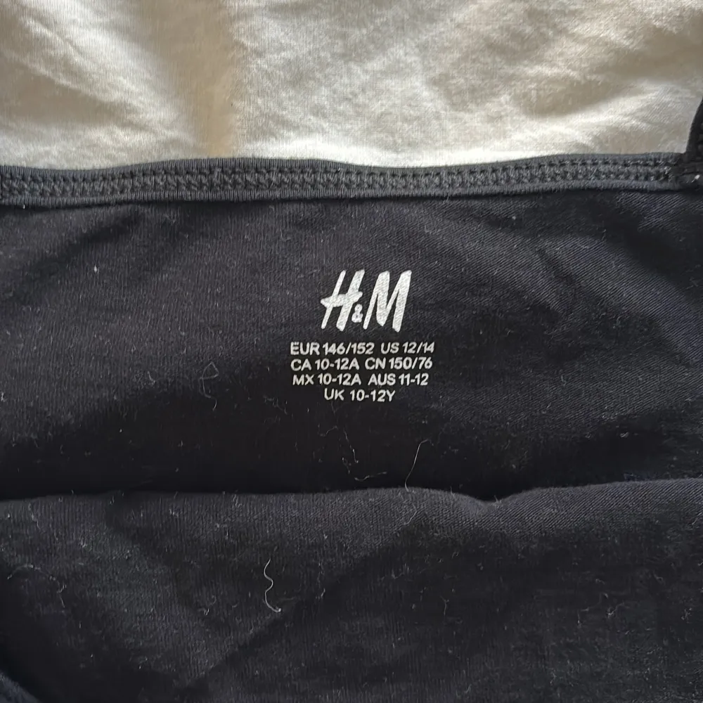 Ett enkel svart linne från H&M med smala axelband. Linnet har en rak passform och är tillverkad i mjukt material, perfekt för sommardagar eller som basplagg. Stilren och lätt att matcha med olika accessoarer. Säljer en likadan i grå . Yläosat.