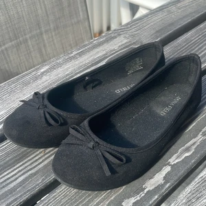 Svarta ballerinaskor med rosett från Anna Field - Säljer ett par klassiska svarta ballerinaskor från Anna Field. Skorna har en söt rosettdetalj framtill och rund tå. Perfekta att matcha med både jeans och klänning. Superenkla att bara dra på sig och sticka ut.