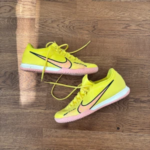 Gula Nike fotbollsskor - Snygga gula Nike fotbollsskor med rosa sula och svart logga. Skorna har snörning och är perfekta för inomhusspel. Har inte använt de så mycket, max 10 gånger. Köpte dessa för länge sen. Pris kan diskuteras