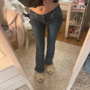 Blå bootcut jeans - Snygga blå bootcut jeans med låg midja. Perfekta för en avslappnad stil. Klassisk design med fem fickor och knappgylf.
